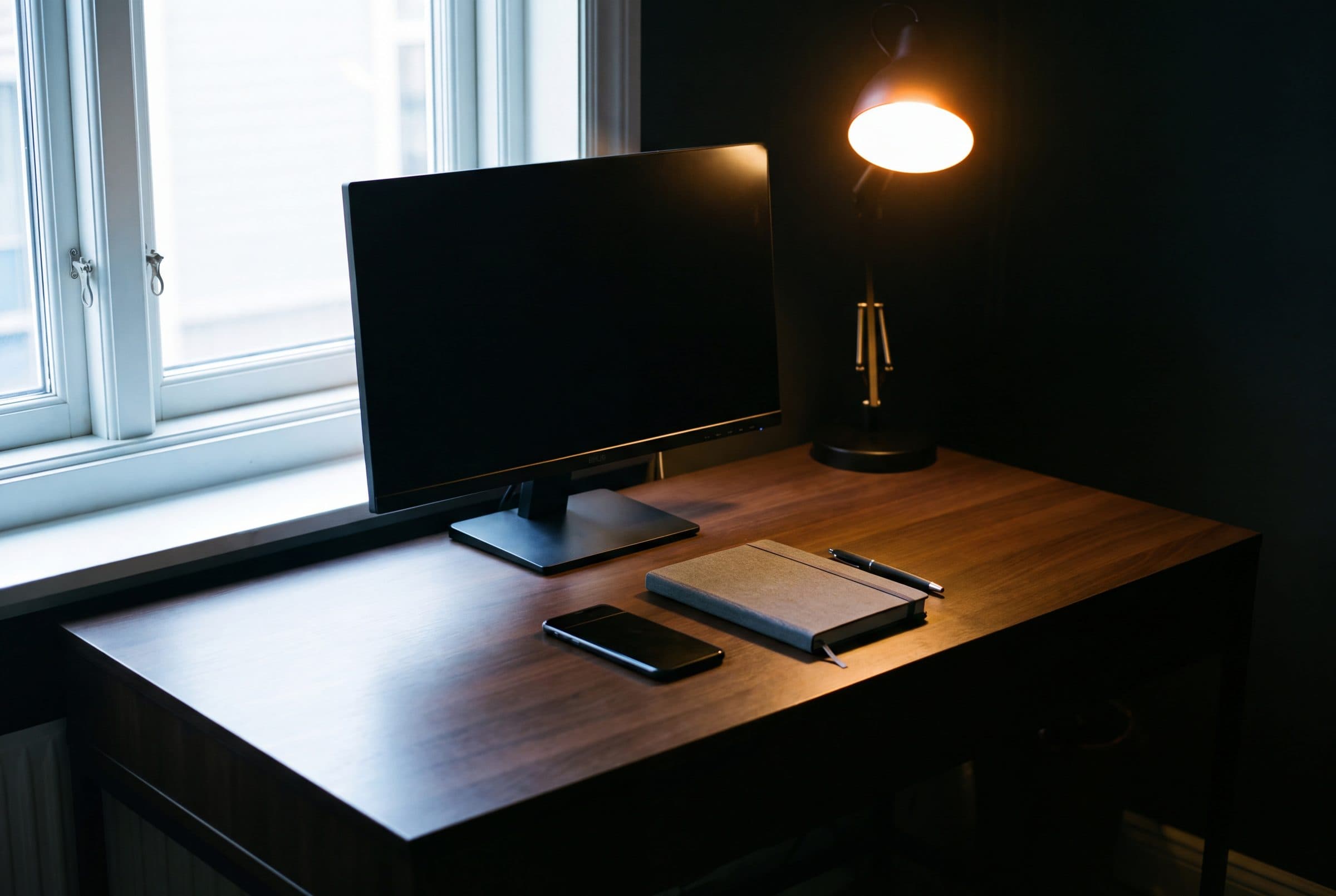 A tidy contemporary desk ready for the working day, amber lamp lit at the edge of frame